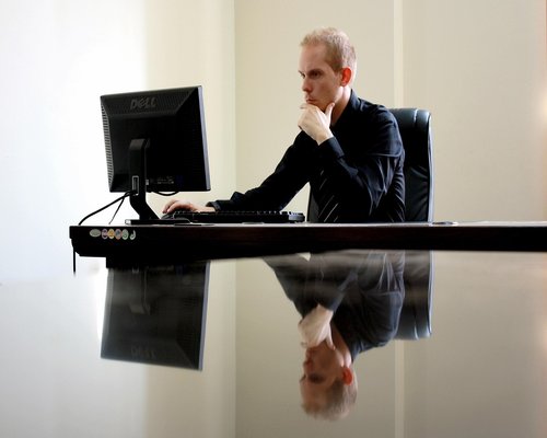 Man adjusting monitor height at standing desk